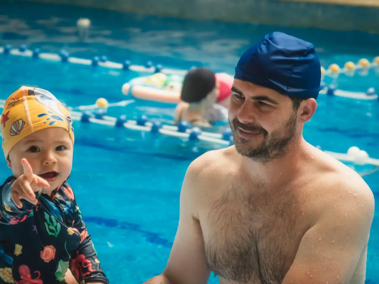 Child learning to swim with instructor in indoor pool