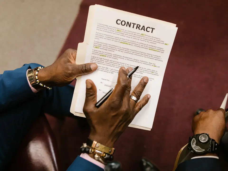 Hands holding a contract with a pen ready to sign