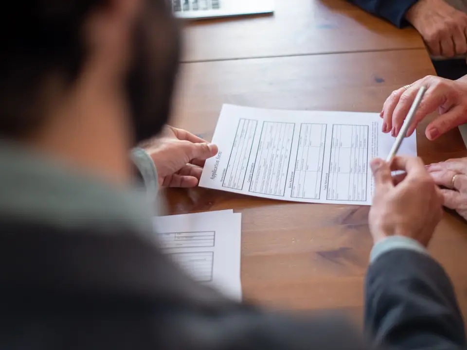 Two people reviewing documents at a wooden table at a meeting