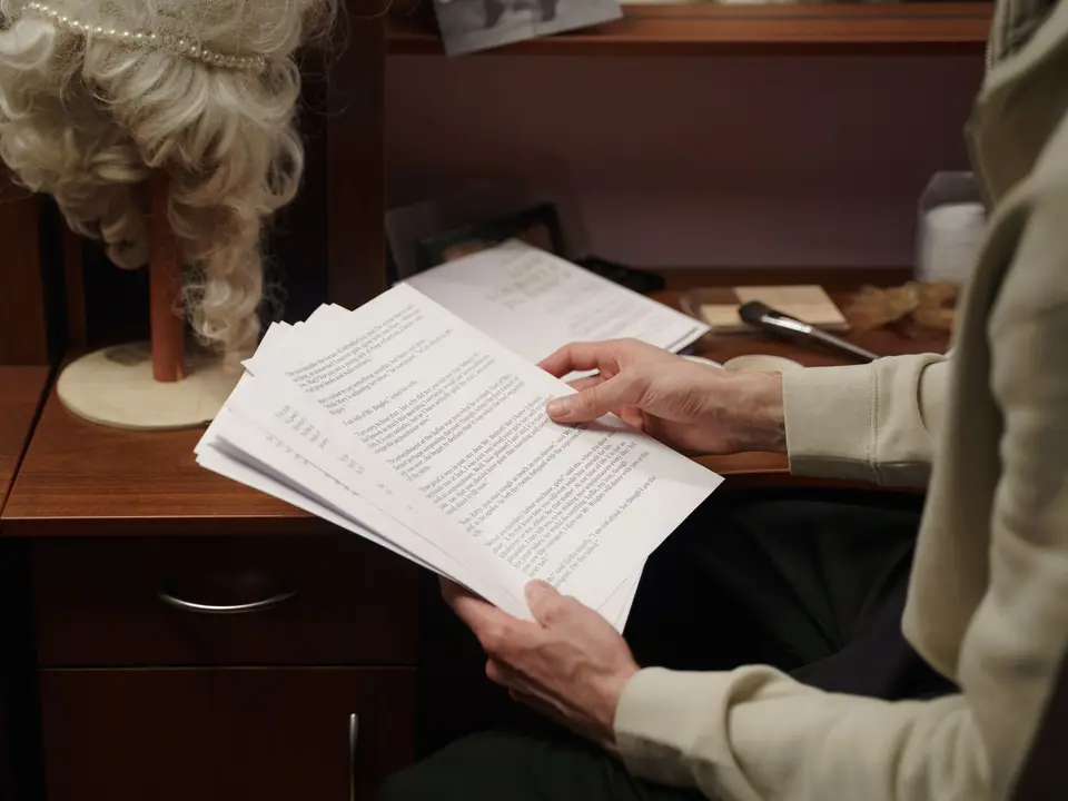 Hands holding a thick script in a backstage dressing room