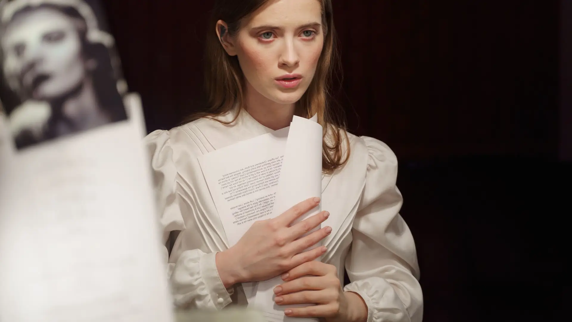 Actress holding a script in a dressing room with headshots pinned to the wall