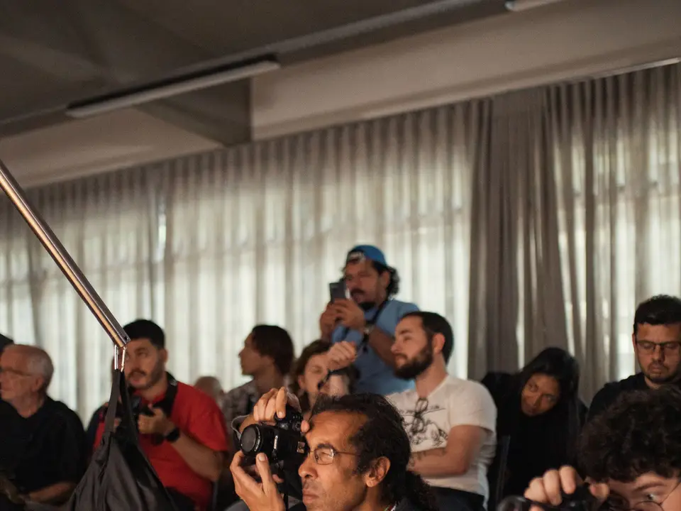 Press photographers aiming cameras and microphones at an event