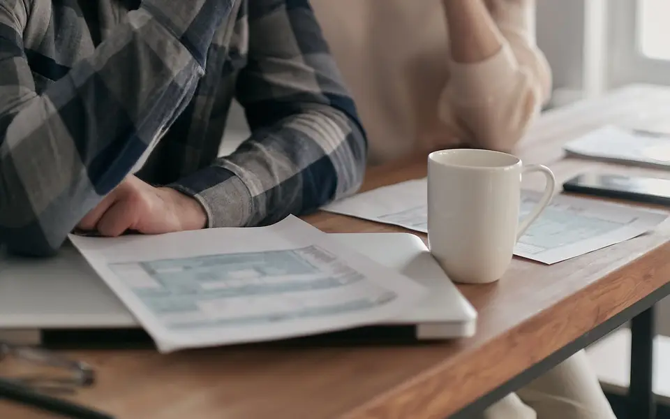 A couple at a table with bills and a phone planning their finances