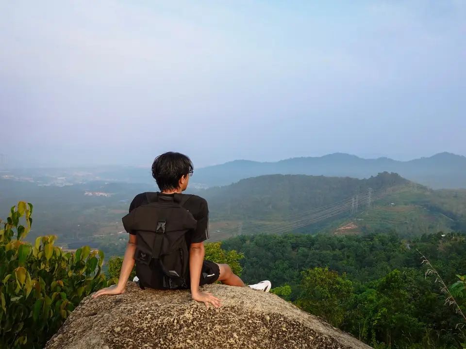 Hiker resting on a rock above a misty green valley