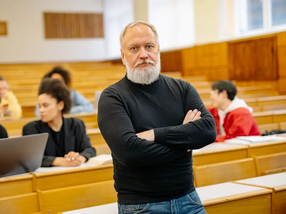 Professor standing in a lecture hall with students at their desks