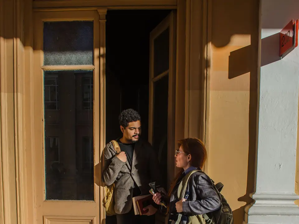 Two students conversing at a university entrance