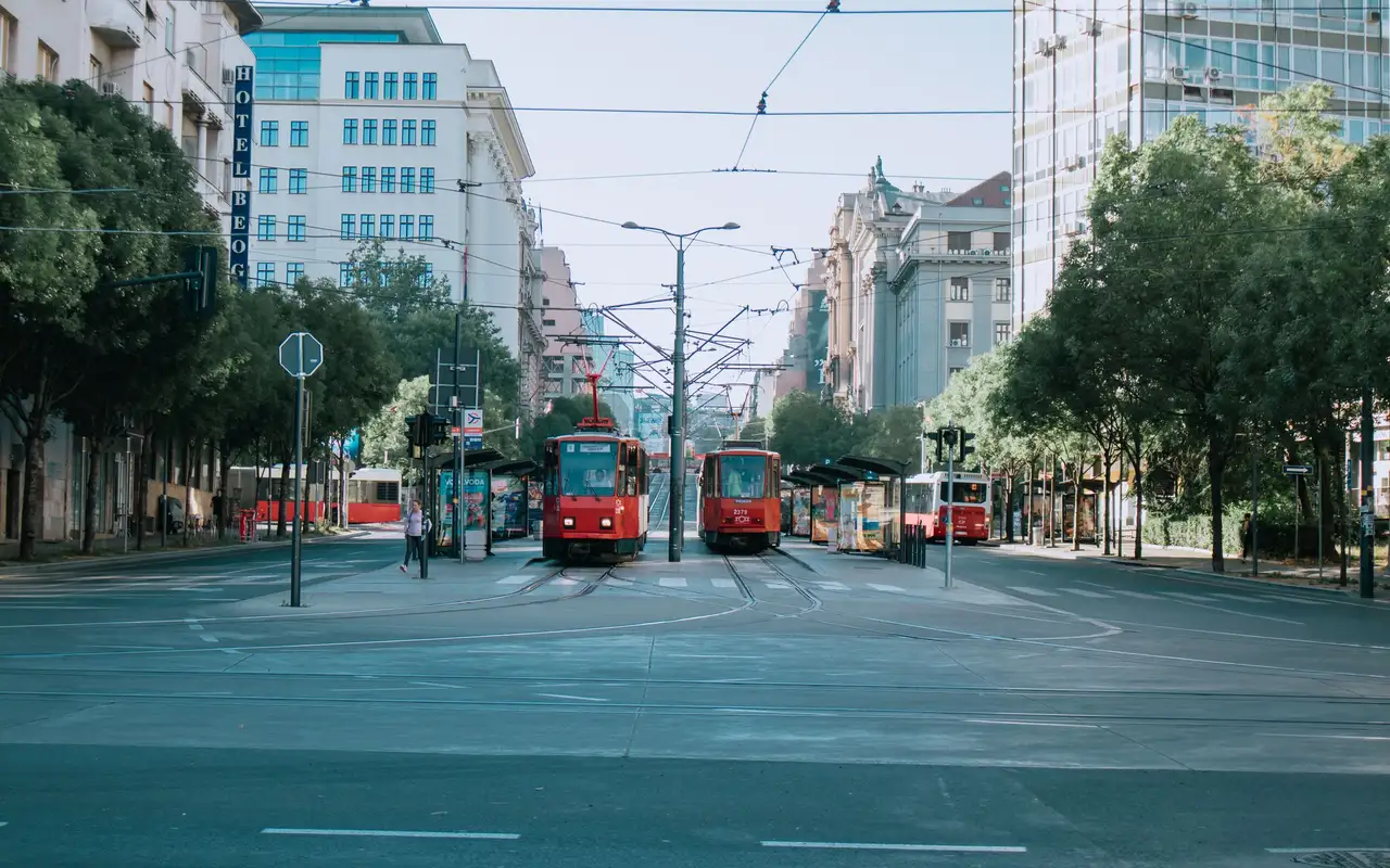 Morning city view with red trams and modern architecture at a mixed-use intersection