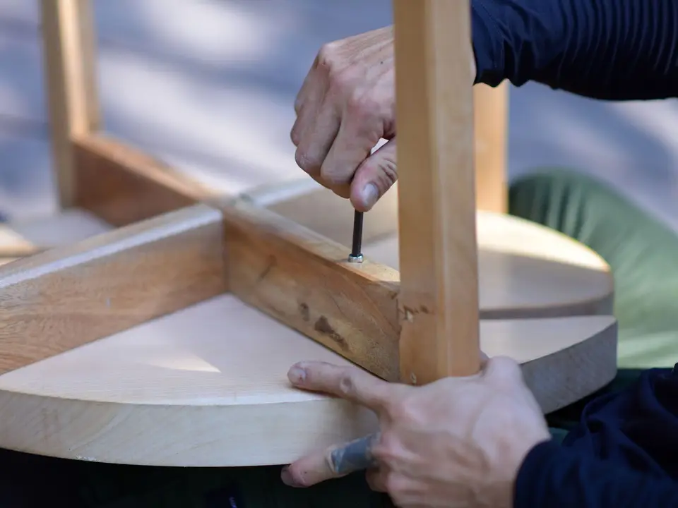 Hands assembling a wooden stool