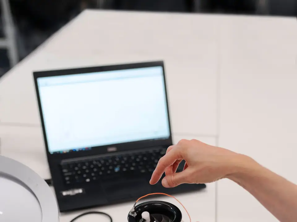 Engineers testing an electronic prototype with a laptop in a lab