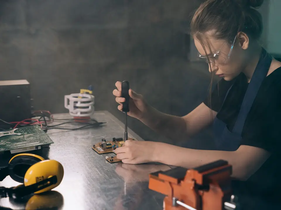 Woman assembling electronic circuits with precision tools in a workshop