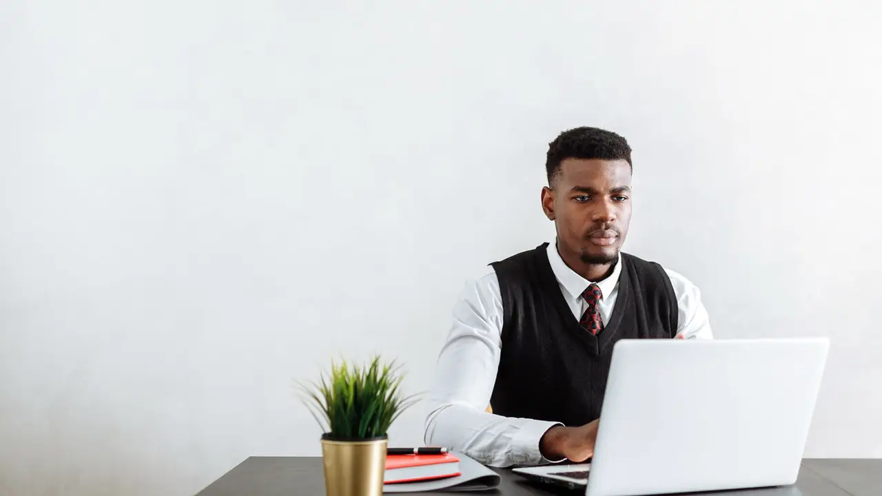 Assistant at a desk with laptop and notes