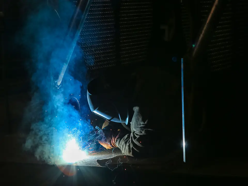 Welder in protective gear with bright sparks