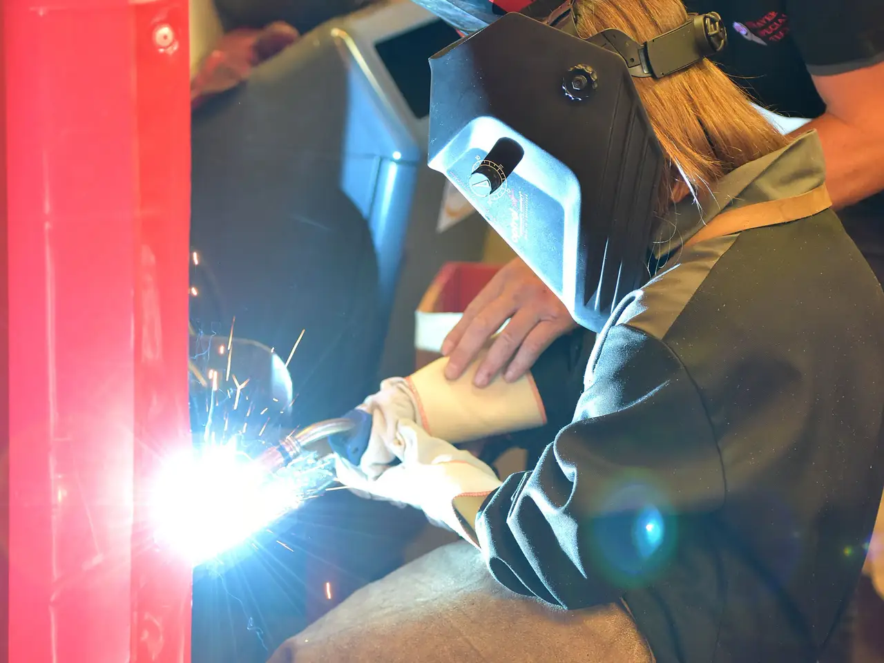 Young female apprentice learning welding in a workshop