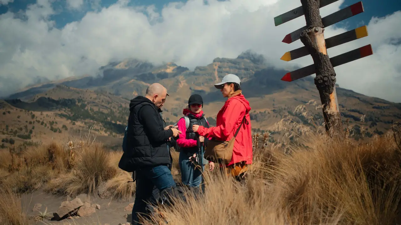 Trail crew leader briefing volunteers at a mountain trail signpost