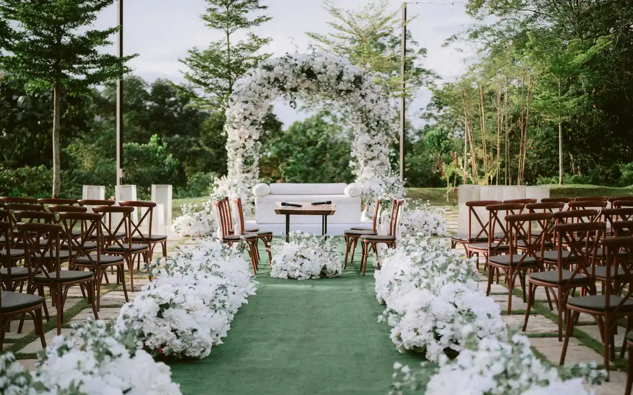 Outdoor ceremony with a floral arch under old trees