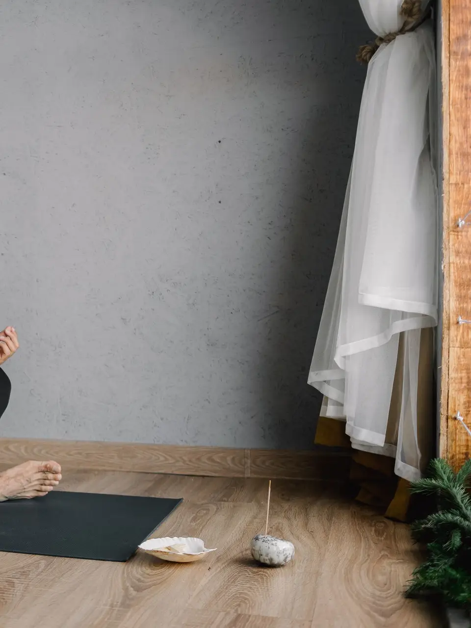 Asian man practicing meditation indoors on a yoga mat, focusing on well-being and mindfulness.
