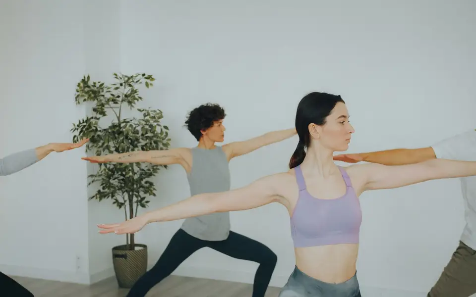 Adults practicing yoga poses in a modern, minimalist studio.