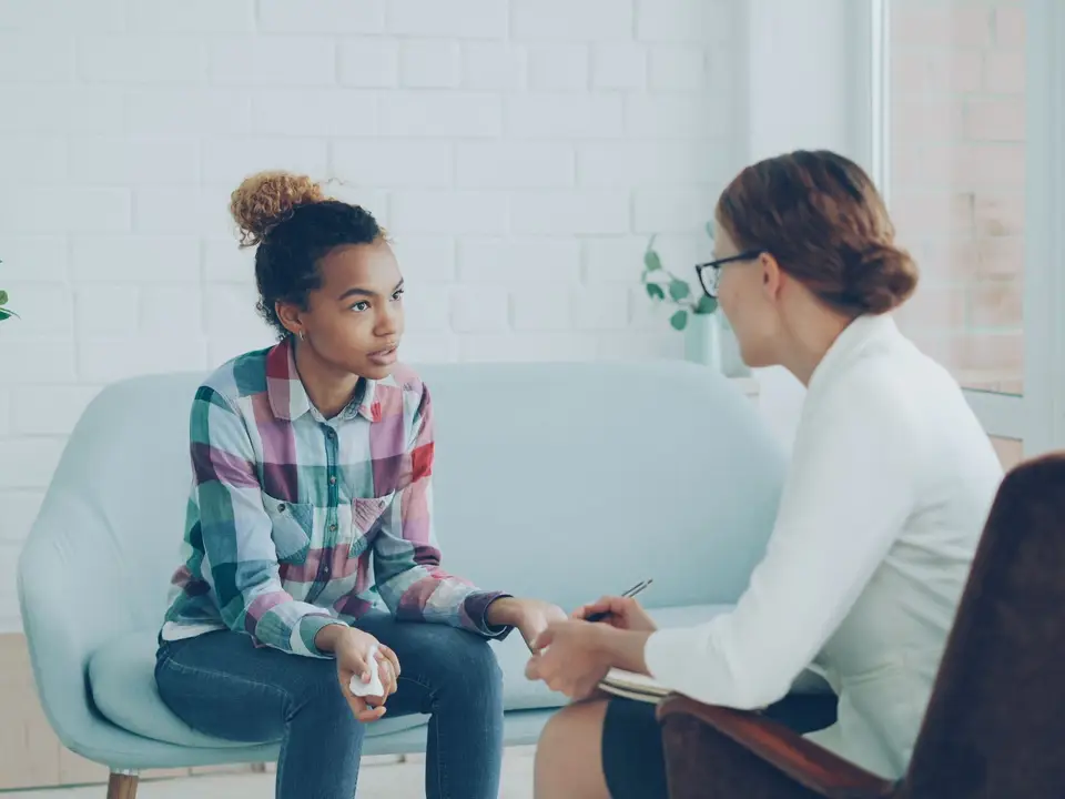 A teenager and therapist having a counseling session in a bright, modern office setting
