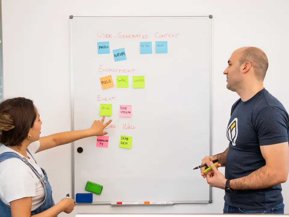 Two people planning with sticky notes on a whiteboard
